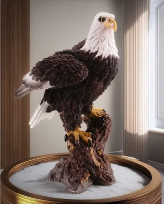 A detailed figurine of a bald eagle perched on a branch, displayed indoors with soft lighting.
