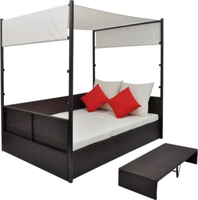 A brown poly rattan garden bed with a white canopy and red and white cushions, shown with a matching coffee table, against a white background.