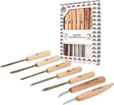 A set of wood carving chisels and knives are displayed in front of their packaging.