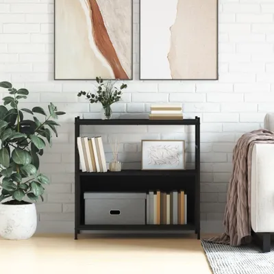 A black bookshelf filled with books and decorative items, placed against a white brick wall next to a sofa.
