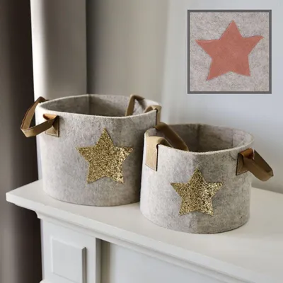 Two felt storage baskets with star embellishments placed on a white shelf.