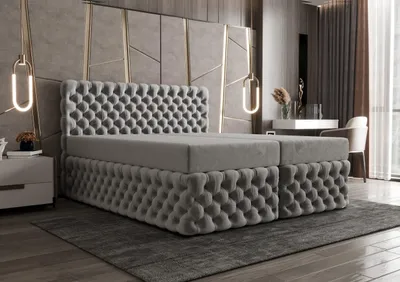 A luxurious bedroom with a tufted boxspring bed, bedside table, and a vanity area.