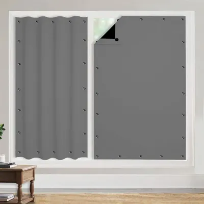 Two portable blackout curtains are shown hanging in a window frame. The left curtain is fully closed, while the right curtain is partially open, revealing a glimpse of the outside through the window.