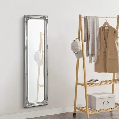 A full-length mirror and a clothing rack with clothes and accessories.