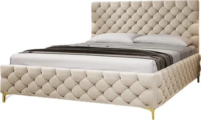 A studio shot of a tufted bed with a mattress and bedding.