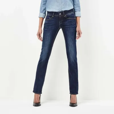 A person wearing jeans and a denim shirt, standing against a white background.