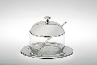 A silver-plated glass jam jar with a spoon and saucer, presented on a plain white background.
