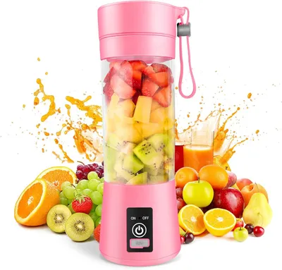 A pink portable blender filled with various fruits, surrounded by fresh fruits and juice splashes.