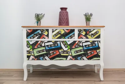 A dresser with drawers decorated with a cassette tape pattern, placed against a white wall.