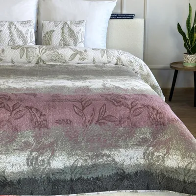 A close-up view of a bed with a patterned comforter and pillows.