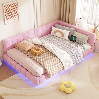 A pink upholstered daybed with LED lighting and USB ports, set up in a bedroom with decorative pillows and a rug.