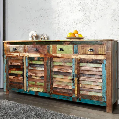 A colorful, rustic sideboard with multiple drawers and doors, set against a textured gray wall.