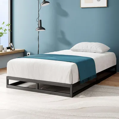Schwarzer Metallbettrahmen mit Matratze in modernem Schlafzimmer mit blauer Wand.
