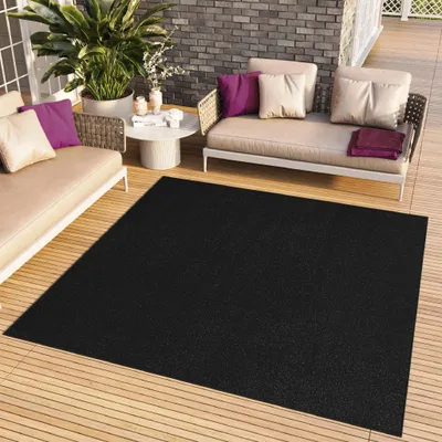 A black rug on a wooden deck with outdoor furniture.