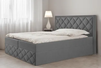 A dark gray upholstered bed with a diamond-stitched headboard and base, shown in a bedroom setting with sheer curtains and a bedside lamp.
