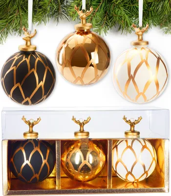 Three Christmas ornaments with gold deer heads are displayed hanging from a pine branch, and then in a gift box.