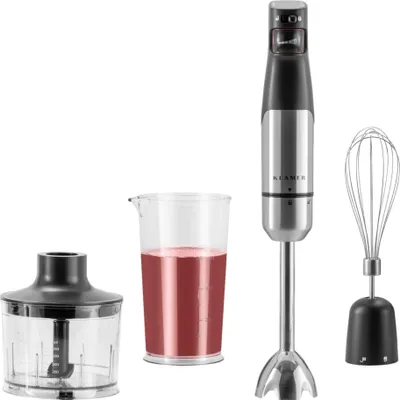 A set of kitchen appliances including an immersion blender, a measuring cup with red liquid, and a whisk attachment, all displayed against a white background.