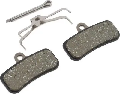 A set of bicycle disc brake pads and a spring clip, laid out on a white background.