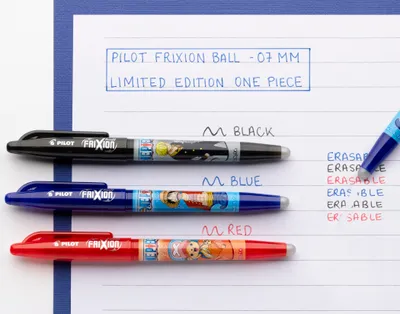 Three pens of different colors (black, blue, red) are laid out on a white lined paper, with some text written on the paper.