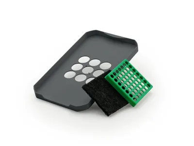 A gray lid, a black filter, and a green tray are arranged on a white background.