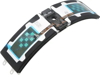 A close-up view of a curved electronic component, likely a battery or circuit board, with visible green square elements and flexible ribbon cables.