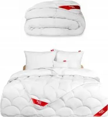A folded duvet and a made-up bed with pillows and a duvet.