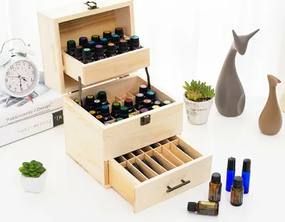 A wooden storage box with multiple compartments, filled with small bottles, likely essential oils or nail polish, is displayed on a white surface.