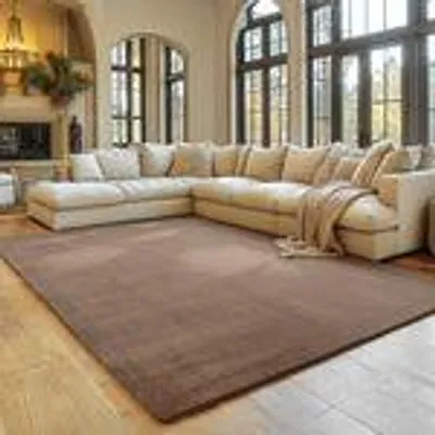 A spacious living room with a large sectional sofa and a plush rug.