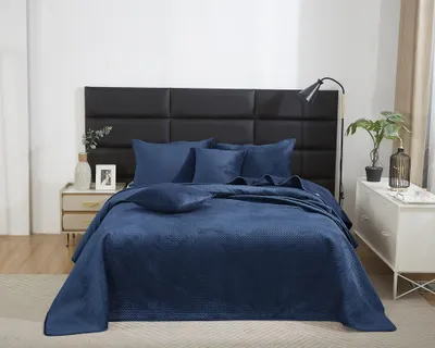 A bed with blue bedding and pillows, set against a black headboard.