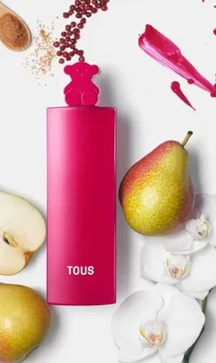 A pink perfume bottle with a teddy bear cap is surrounded by pears, orchids, and spices.