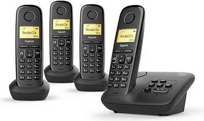 Four black cordless phones are shown on their charging bases, with one phone in the foreground on its base.