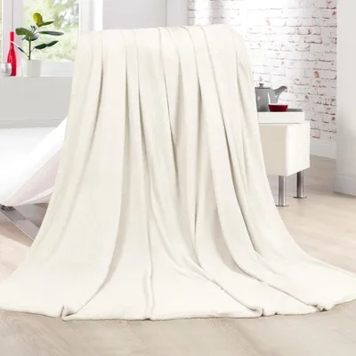 A cream-colored blanket is draped over a piece of furniture, with a window and a brick wall in the background.
