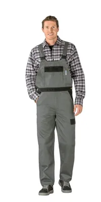 A man wearing gray overalls and a plaid shirt, standing against a white background.