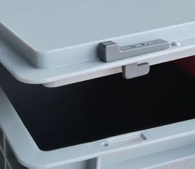 A close-up view of a gray plastic latch mechanism on a light gray storage container lid.