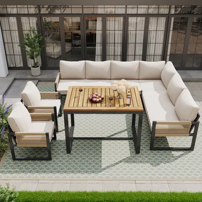 An outdoor patio set with a sectional sofa, chairs, and a dining table, set on a patterned rug.