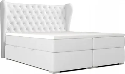 A white upholstered bed with a tufted headboard and a mattress topper.