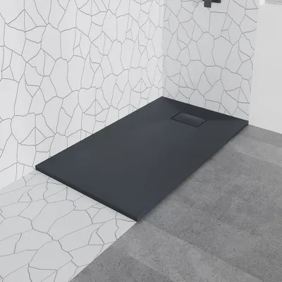 A modern shower tray with a dark gray stone-look finish is shown in a bathroom setting with white tiled walls.