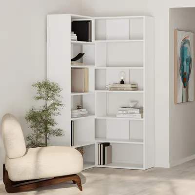 A white corner bookshelf unit is shown in a room with a chair and a painting on the wall.