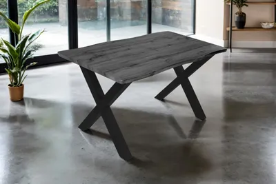 A dining table with a wood-look top and black metal legs is shown in a modern room with large windows.