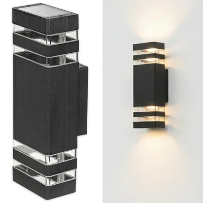 A product shot of a black outdoor wall light with clear glass accents, shown against a white background. To the right, the same light is shown mounted on a white wall, illuminating upwards and downwards.