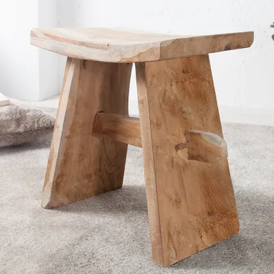 A wooden stool on a carpeted floor.