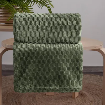 A folded olive green blanket with a textured pattern is displayed on a wooden table.