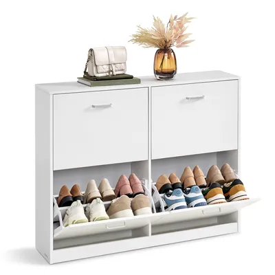 A white shoe cabinet with multiple compartments and shoes displayed inside, along with a handbag and a vase with dried flowers on top.