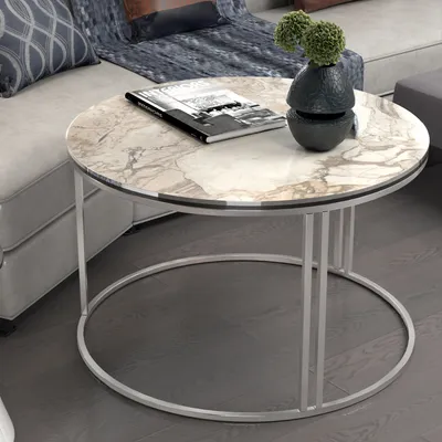A round marble coffee table with a silver metal frame is placed in a living room setting next to a sofa.