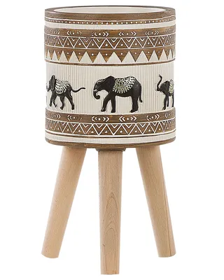 A cylindrical planter with an elephant motif and tribal patterns, supported by three wooden legs.