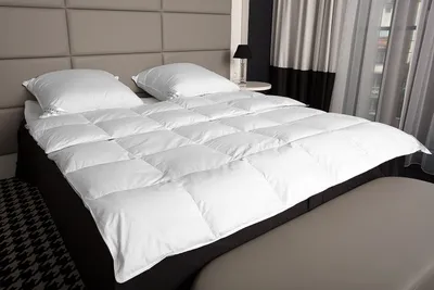 A neatly made bed with a white duvet and two pillows.