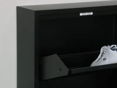 A close-up view of a black metal shoe cabinet with a white sneaker inside.
