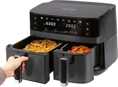 A dual-chamber air fryer with one drawer being pulled out by a hand.