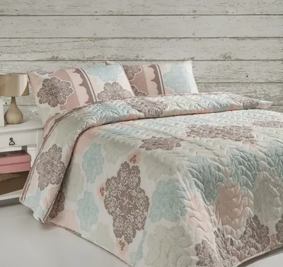 A bed with a patterned quilt and pillows.