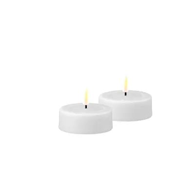 Two white tea lights with lit wicks on a white background.